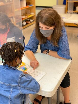 Ms. Jessie works with a student at their desk 