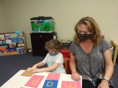 Ms. Kelly helps a student learn letters with blue and pink cards