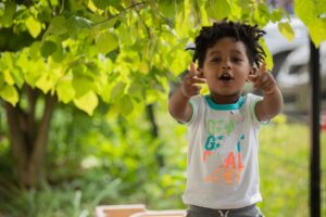 A child outside stretches his arms out toward the camera