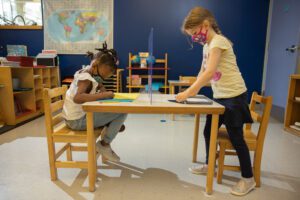 two children at a table working on a project