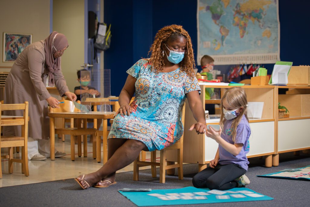 Miss Sabrina points to a notecard in a child's hand