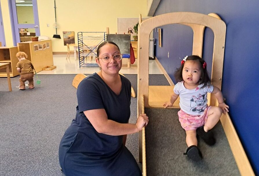 Woman and child sit facing forward on a slide.