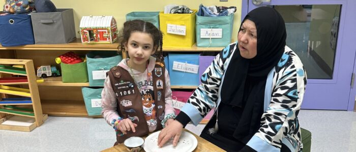 young girl and teacher in black hijab sit at table together